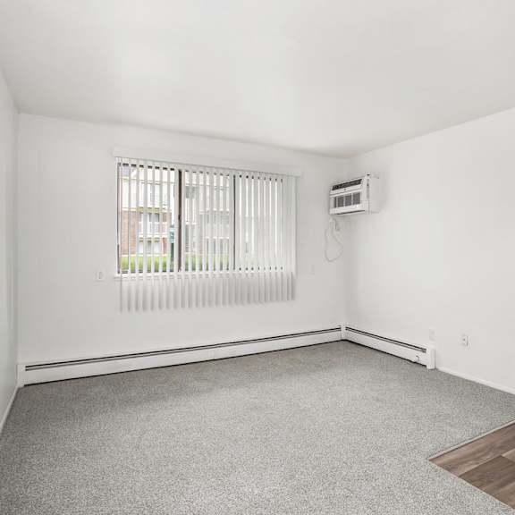 Thumbnail 8 of 19 A living room with a window and plush carpet at Brookside Apartments, Springfield