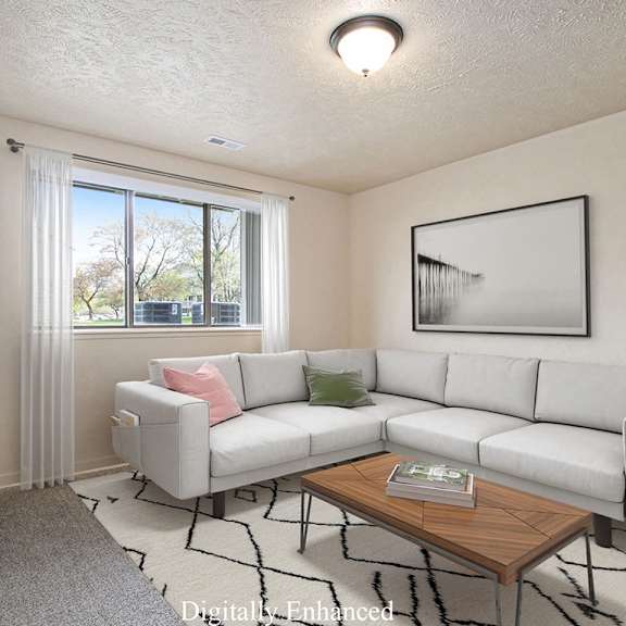 Thumbnail 3 of 7 A living room with a grey couch, a wooden coffee table, and a large window with curtains at Brookside Apartments, Springfield, MI