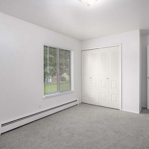 Thumbnail 10 of 13 A bedroom with white walls and a window with blinds at Brookside Apartments, Springfield
