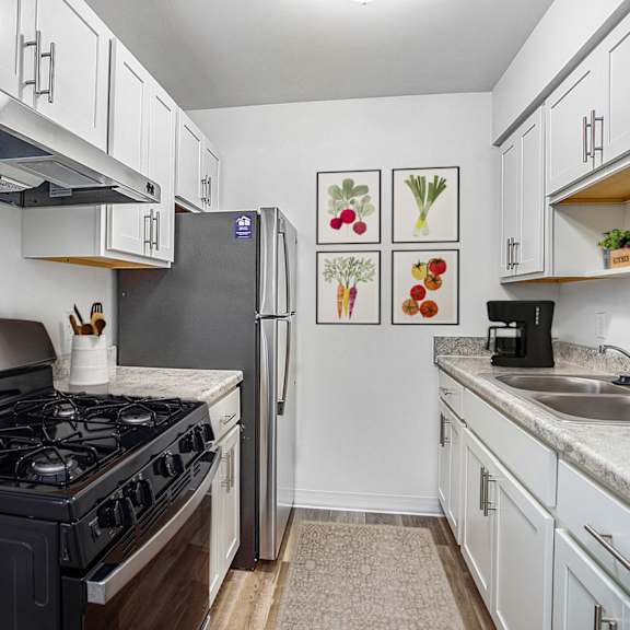 Thumbnail 7 of 13 A kitchen with a stainless steel stove top and refrigerator at Brookside Apartments, Springfield