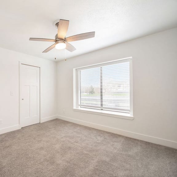 Thumbnail 13 of 14 A bedroom with a large window and ceiling fan at Byron Lakes Apartments, Byron Center, 49315