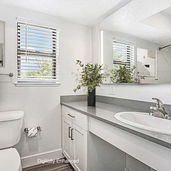 Thumbnail 11 of 14 A bathroom with a window, sink, and mirror at Byron Lakes Apartments, Michigan, 49315