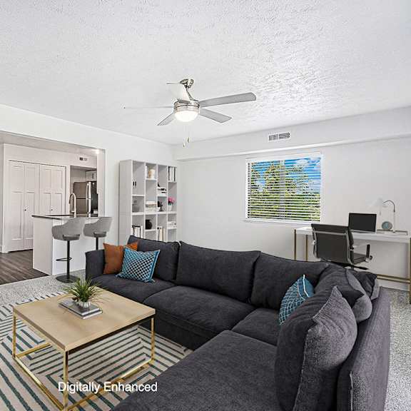 Thumbnail 5 of 14 An enlarged living room with a grey couch and a coffee table at Byron Lakes Apartments, Michigan, 49315