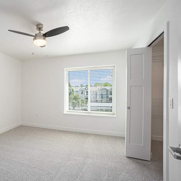 Thumbnail 13 of 14 A bedroom with a large window and ceiling fan at Byron Lakes Apartments, Byron Center, 49315