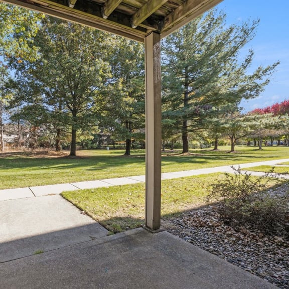 Thumbnail 6 of 19 private patio overlooking park like grounds with trees at Byron Lakes Apartments in Byron Center, MI