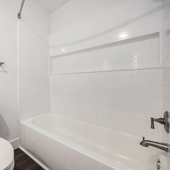 Thumbnail 16 of 24 a white bathroom with a toilet and a tub at Byron Lakes Apartments in Byron Center, MI