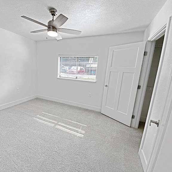 Thumbnail 18 of 24 A bedroom with a ceiling fan and a window with blinds at Byron Lakes Apartments, Michigan, 49315