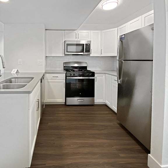 Thumbnail 12 of 24 A modern kitchen with stainless steel appliances and white cabinets at Byron Lakes Apartments, Michigan, 49315
