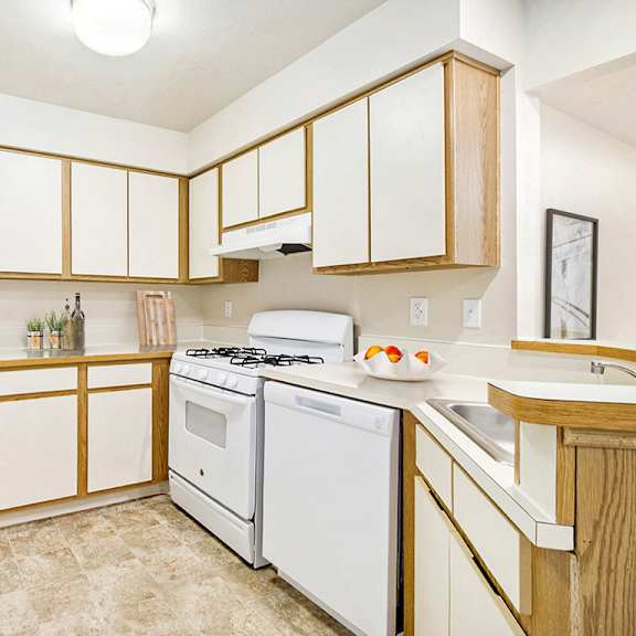 Thumbnail 6 of 12 A kitchen with white appliances and wooden cabinets at Canal Club Apartments, Lansing, 48917