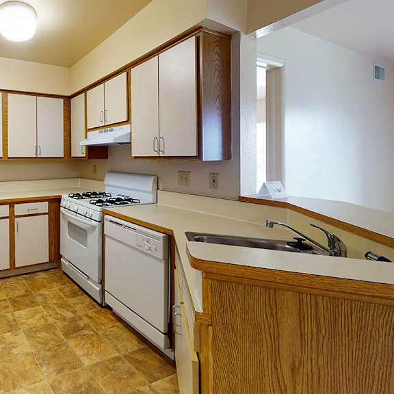 Thumbnail 5 of 8 A kitchen with white appliances and wooden cabinets at Canal Club Apartments, Lansing, 48917