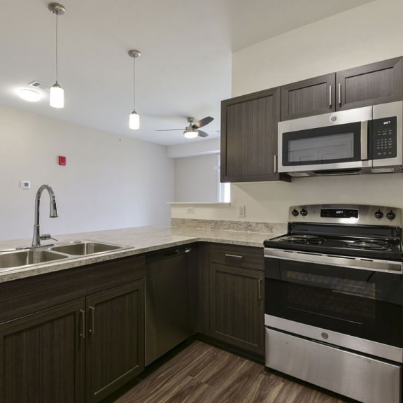 Thumbnail 10 of 18 A kitchen with stainless steel appliances and a breakfast bar at Chase Creek Apartment Homes, Alabama, 35811