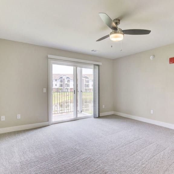 Thumbnail 5 of 12 A living room with plush carpet, a ceiling fan, and access to a balcony at Chase Creek Apartment Homes, Huntsville, 35811