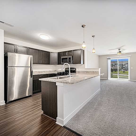Thumbnail 4 of 18 A kitchen with a refrigerator, microwave, and a breakfast bar with a sink at Chase Creek Apartment Homes, Huntsville, 35811