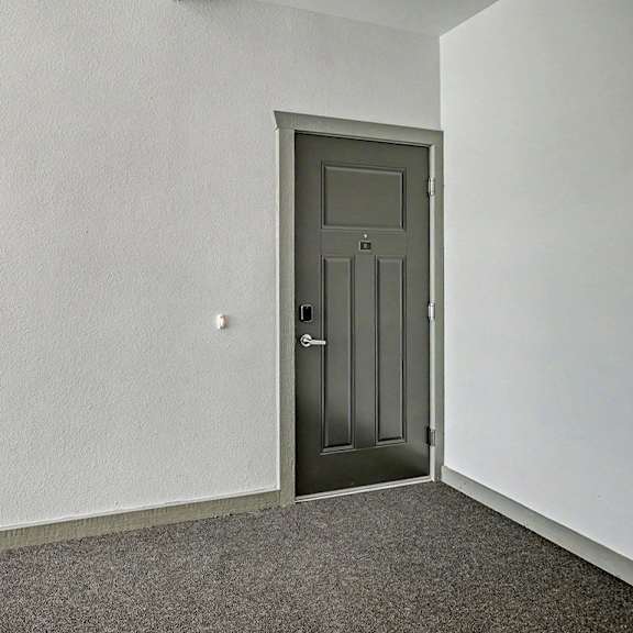 Thumbnail 3 of 13 An apartment entryway with a grey door is in a hallway with carpet at Chase Creek Apartment Homes in Huntsville, AL