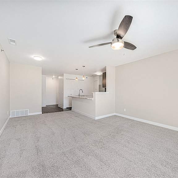 Thumbnail 6 of 18 A living room with a ceiling fan and carpeted floor at Chase Creek Apartment Homes, Huntsville, 35811
