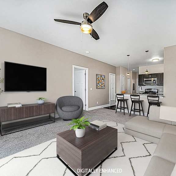 Thumbnail 4 of 12 A living room with a grey armchair, a white sofa, a wooden coffee table, and a television on the wall