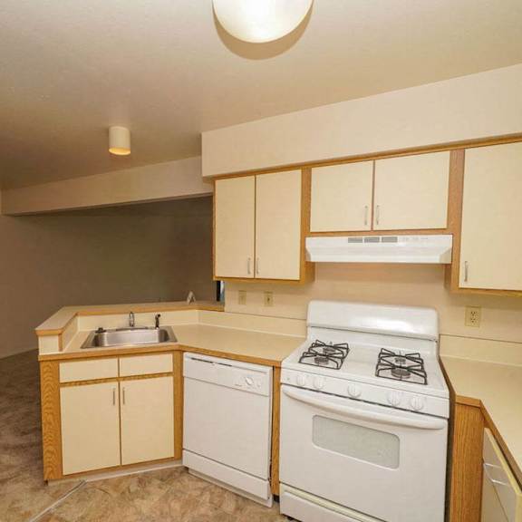 Thumbnail 8 of 12 A kitchen with a white gas stove and dishwasher at Canal Club Apartments, Michigan