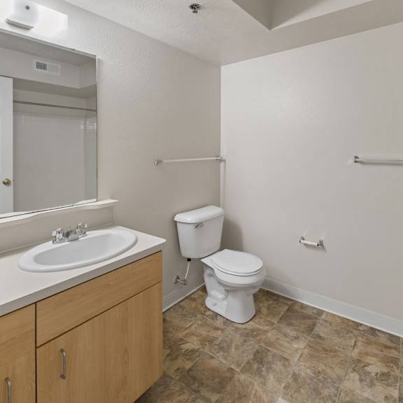 Thumbnail 4 of 6 A bathroom with a toilet, sink, and mirror at Colonial Pointe at Fairview Apartments, Bellevue, NE, 68123