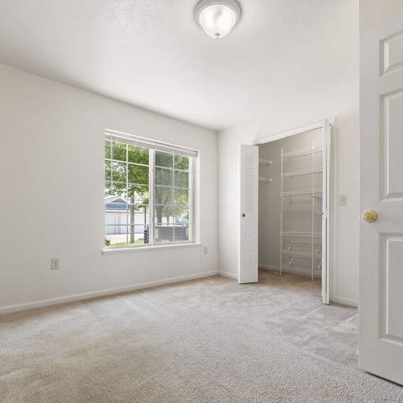 Thumbnail 5 of 6 A bedroom with a large window and walk-in closet at Colonial Pointe at Fairview Apartments, Bellevue, NE, 68123