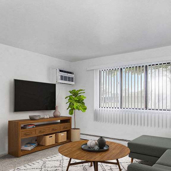 Thumbnail 4 of 10 A garden style living room with a grey couch, a coffee table, a television, and a plant at Concord Place Apartments in Kalamazoo, Michigan 49009