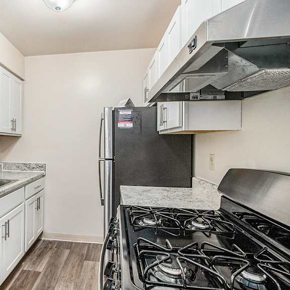 Thumbnail 10 of 15 An upgraded kitchen with white cabinets and stainless steel appliances at Concord Place Apartments, Kalamazoo, 49009black gas stove.