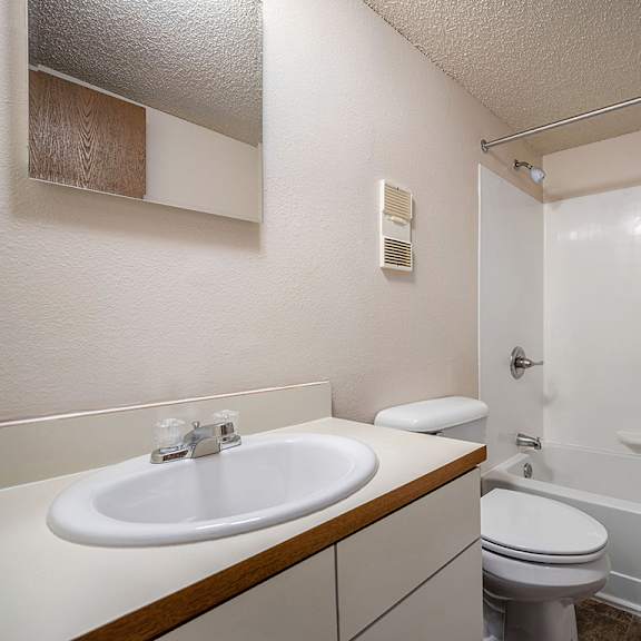 Thumbnail 12 of 14 A bathroom with a toilet next to a sink and a bathtub at Concord Place Apartments, Kalamazoo, MI, 49009