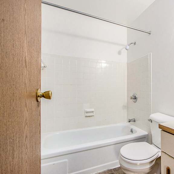 Thumbnail 11 of 15 A bathroom with a bathtub/shower, vanity with sink, and toilet at Concord Place Apartments, Kalamazoo, MI