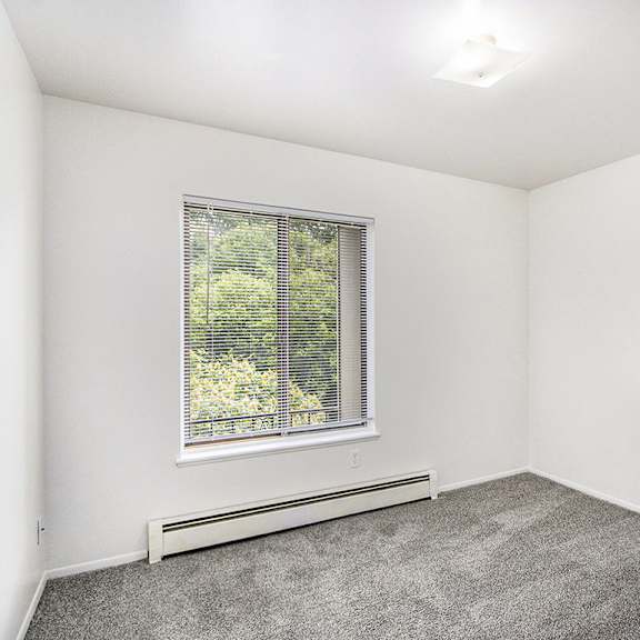 Thumbnail 13 of 15 A bedroom with a window and plush carpeting at Concord Place Apartments, Kalamazoo, MI
