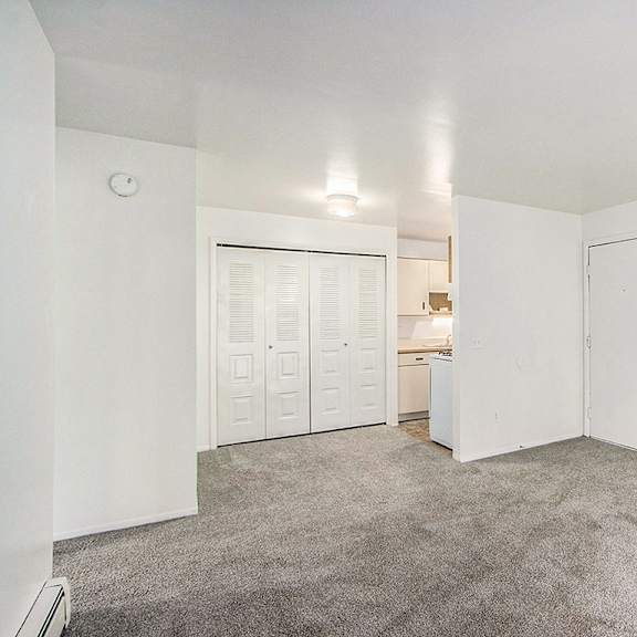 Thumbnail 5 of 15 A large empty living/dining room with a carpeted floor and a large closet at Concord Place Apartments, Kalamazoo, MI