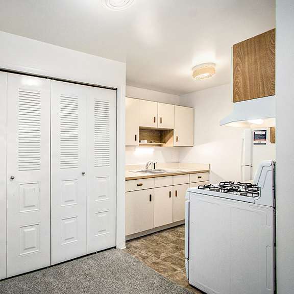 Thumbnail 6 of 15 A kitchen with white appliances and wooden cabinets at Concord Place Apartments, Kalamazoo, MI