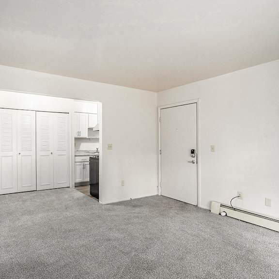 Thumbnail 4 of 15 A living and dining room with a carpeted floor leading to a kitchen at Concord Place Apartments, Kalamazoo, MI
