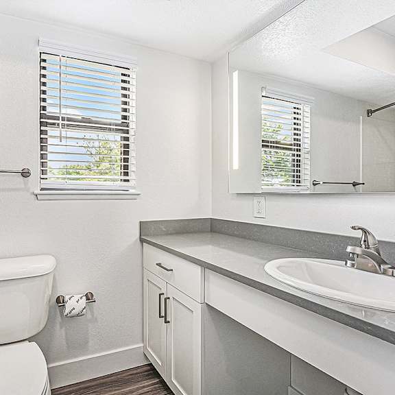 Thumbnail 11 of 13 A white toilet sits next to a sink in a bathroom at The Crossings Apartments in Grand Rapids, MI