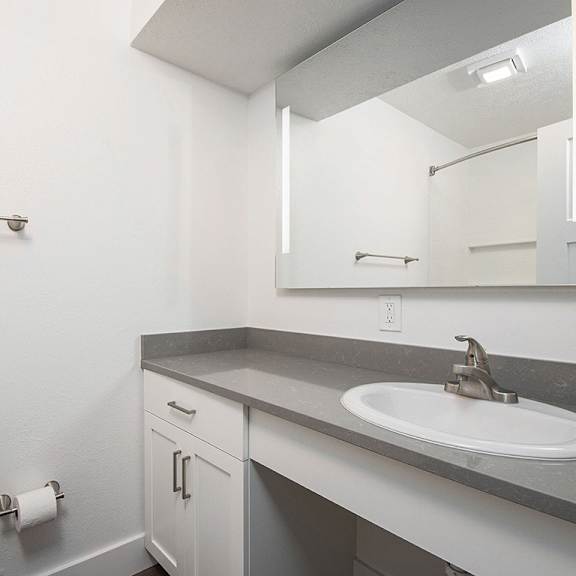 Thumbnail 13 of 16 A renovated bathroom with a large vanity area and mirror at The Crossings Apartments, Grand Rapids