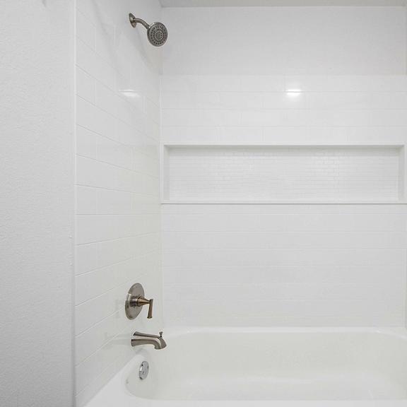 Thumbnail 14 of 16 A white bathroom with a tub and shower at The Crossings Apartments, Grand Rapids