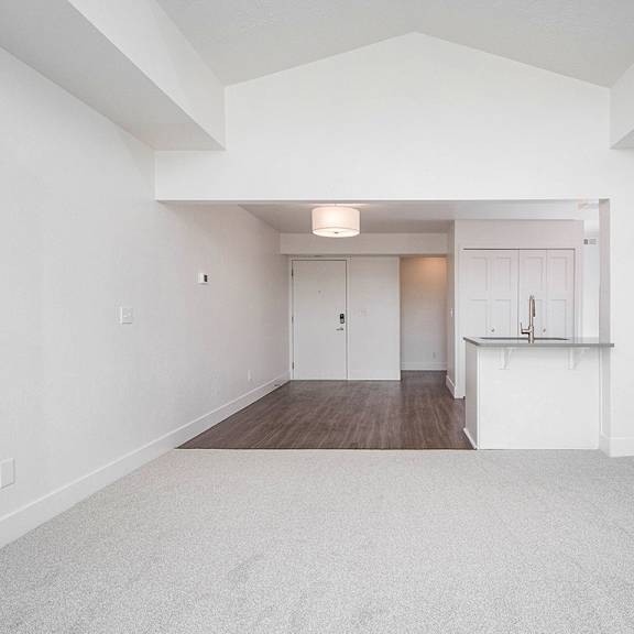 Thumbnail 8 of 16 A large, empty living and dining room with a carpeted floor at The Crossings Apartments, Grand Rapids