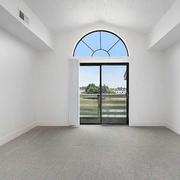 Thumbnail 4 of 16 A living room with a cathedral ceiling and large arched window and a view at The Crossings Apartments, Grand Rapids