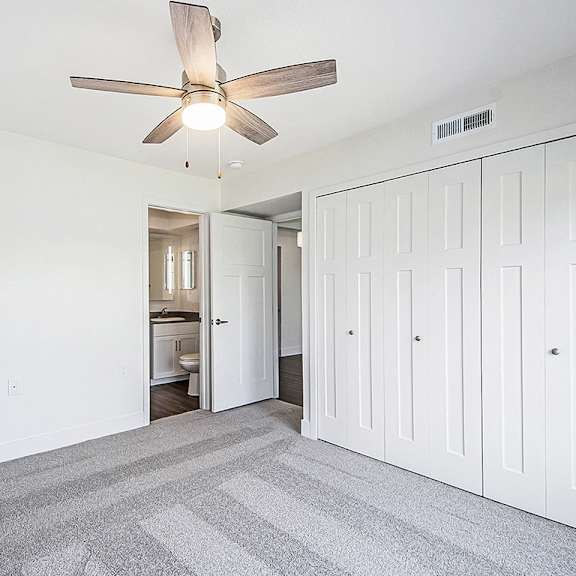 Thumbnail 14 of 15 A bedroom with a ceiling fan and a carpeted floor at The Crossings Apartments in Grand Rapids, MI