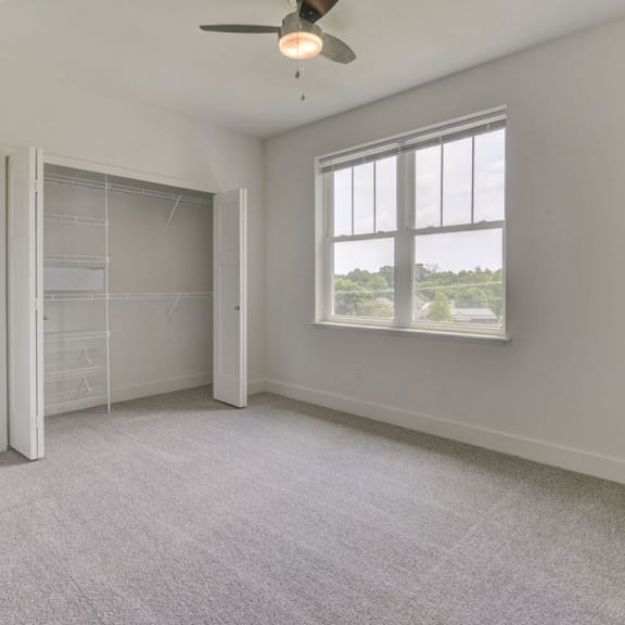 Thumbnail 14 of 14 A spacious bedroom with a ceiling fan and plush carpeting at Dodson Pointe Apartment Homes, Rogers, 72758