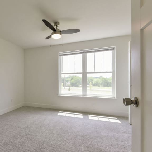 Thumbnail 11 of 12 A spacious bedroom with large windows and a ceiling fan at Dodson Pointe Apartment Homes, Rogers, AR, 72758