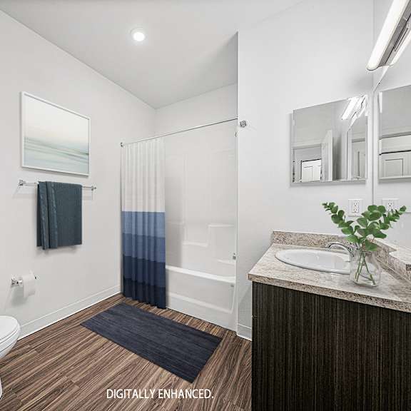 Thumbnail 9 of 13 A bathroom with a toilet, sink, and mirror at Dodson Pointe Apartment Homes, Rogers