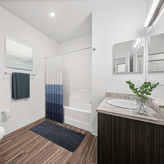 Thumbnail 7 of 11 A bathroom with a toilet, sink, and mirror at Dodson Pointe Apartment Homes, Rogers