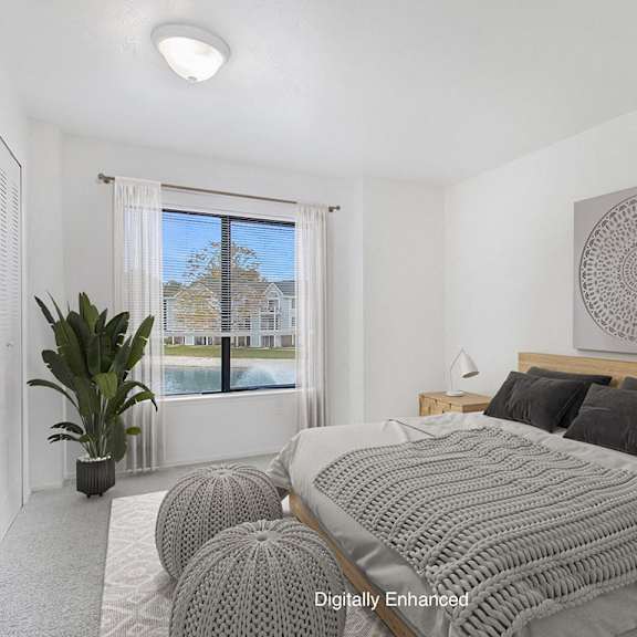 Thumbnail 8 of 13 A bedroom with a large bed and a large window with a view at Dupont Lakes Apartments in Fort Wayne, IN