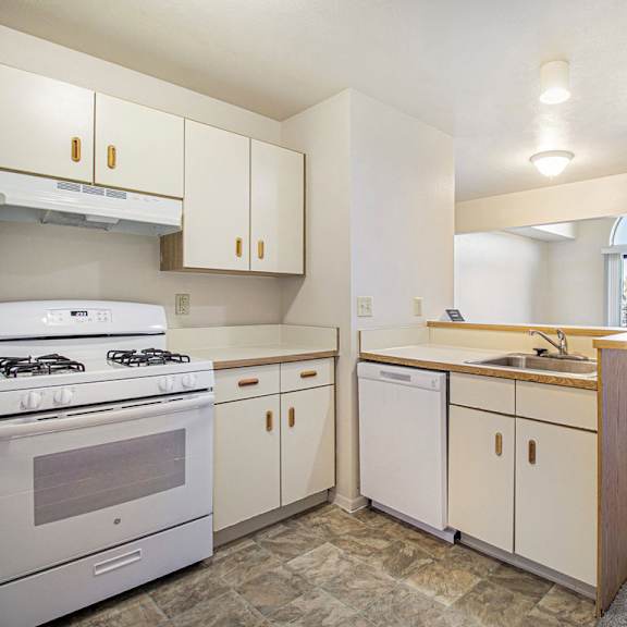 Thumbnail 8 of 16 A kitchen with white appliances and a breakfast bar at Dupont Lakes Apartments in Fort Wayne, IN