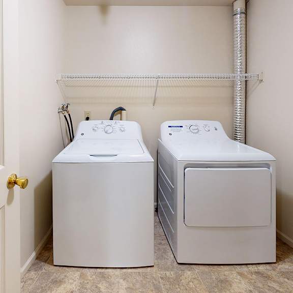 Thumbnail 11 of 16 A full-size washer and dryer in a small laundry room at Dupont Lakes Apartments in Fort Wayne, IN