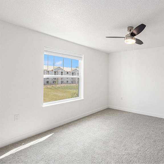 Thumbnail 15 of 18 A bedroom with a ceiling fan and a window showing a view at Eagle Ridge Apartment Homes, Traverse City, MI 49685