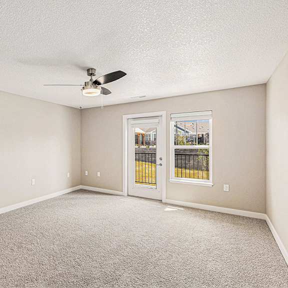 Thumbnail 4 of 18 A living room with a ceiling fan and a french door to the outside at Eagle Ridge Apartment Homes, Traverse City, MI 49685