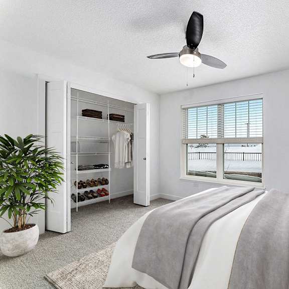 Thumbnail 14 of 14 A bedroom with a large bed, a walk in closet and ceiling fan at Eagle Ridge Apartment Homes, Traverse City, MI 49685