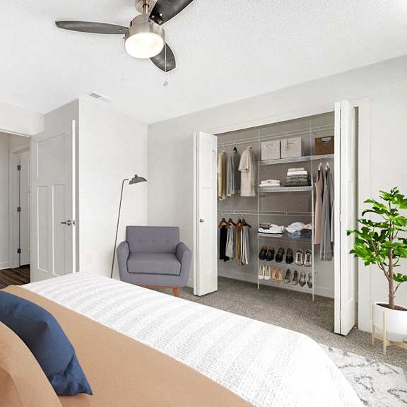 Thumbnail 14 of 15 A bedroom with a bed, chair, and a walk in closet with organizers at Eagle Ridge Apartment Homes in Traverse City, MI