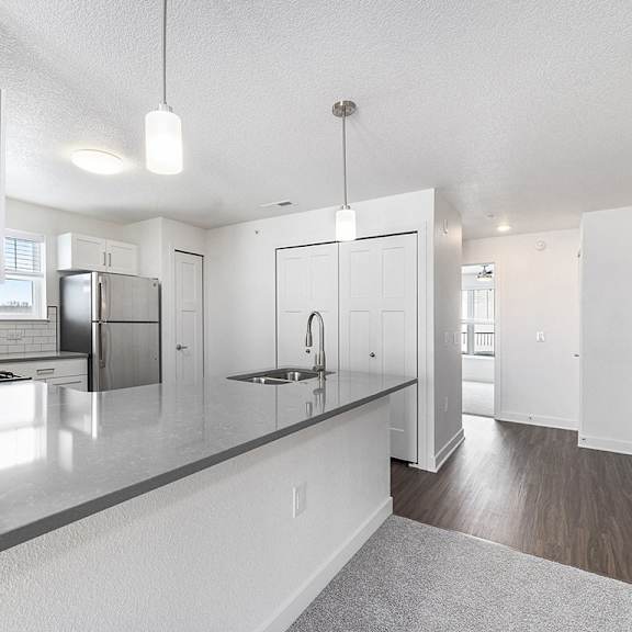 Thumbnail 10 of 15 A modern kitchen with white cabinets and a grey countertop at Eagle Ridge Apartment Homes, Traverse City