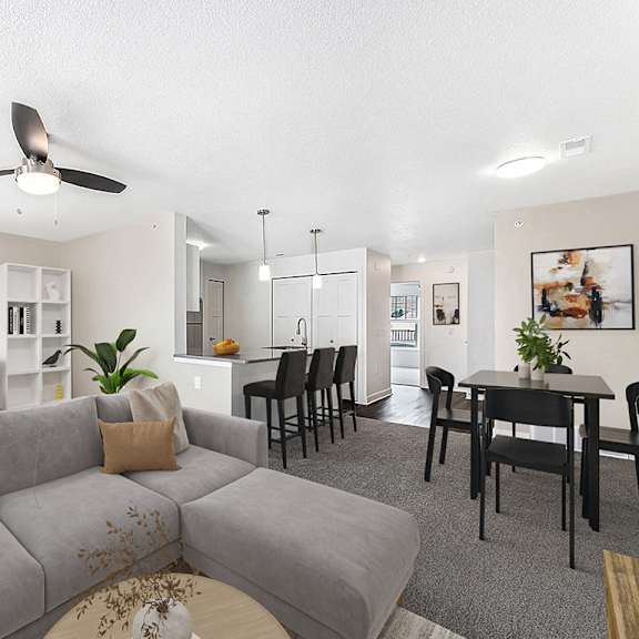Thumbnail 3 of 15 An enlarged living room with a grey couch and a ceiling fan at Eagle Ridge Apartment Homes in Traverse City, MI